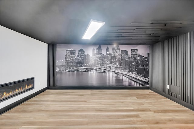 additional living space featuring a glass covered fireplace, a view of city, and wood finished floors