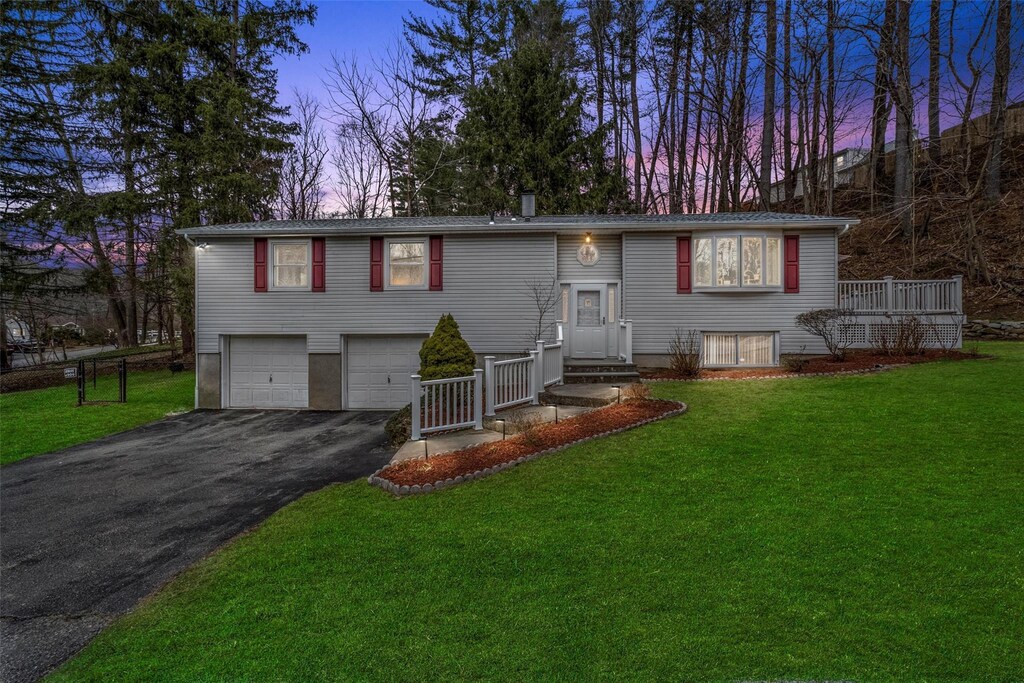 raised ranch with aphalt driveway, a lawn, and an attached garage