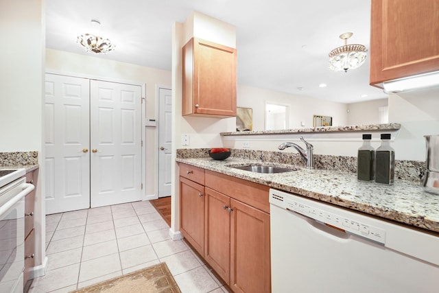 kitchen featuring stove, light stone counters, white dishwasher, light tile patterned flooring, and a sink