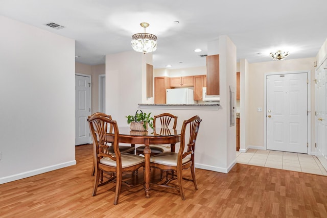 dining space with visible vents, baseboards, light wood-style floors, and a notable chandelier