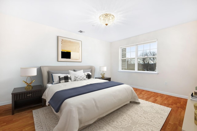 bedroom with visible vents, baseboards, and wood finished floors