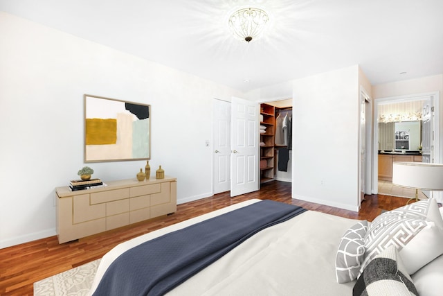 bedroom with wood finished floors, baseboards, and ensuite bathroom