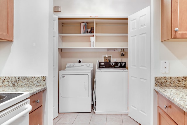 clothes washing area with light tile patterned floors, laundry area, and washer and clothes dryer