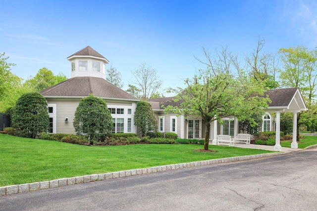 view of front of property with a shingled roof and a front yard