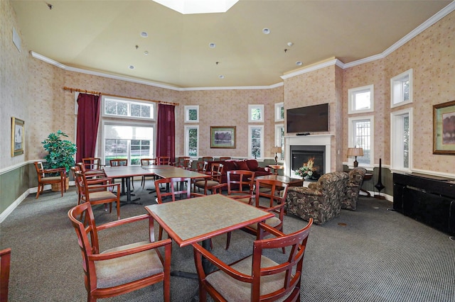 carpeted dining space featuring wallpapered walls, ornamental molding, and a lit fireplace