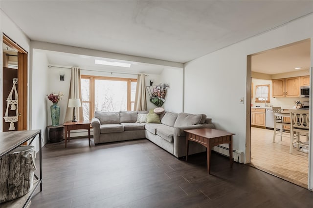 living room featuring baseboard heating and dark wood finished floors