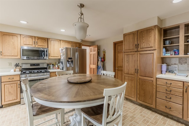 kitchen featuring recessed lighting, brick floor, stainless steel appliances, light countertops, and tasteful backsplash