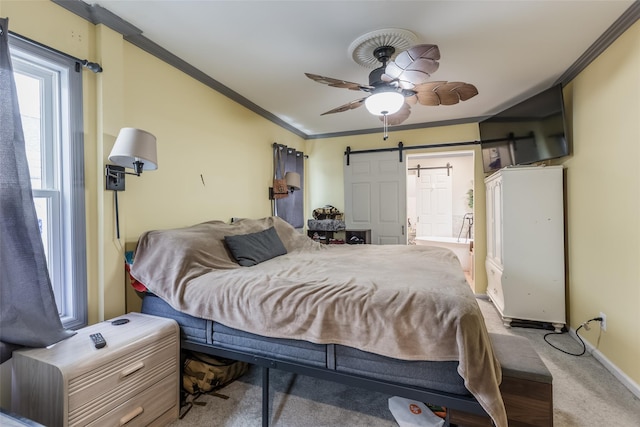 carpeted bedroom with ceiling fan, a barn door, baseboards, and ornamental molding