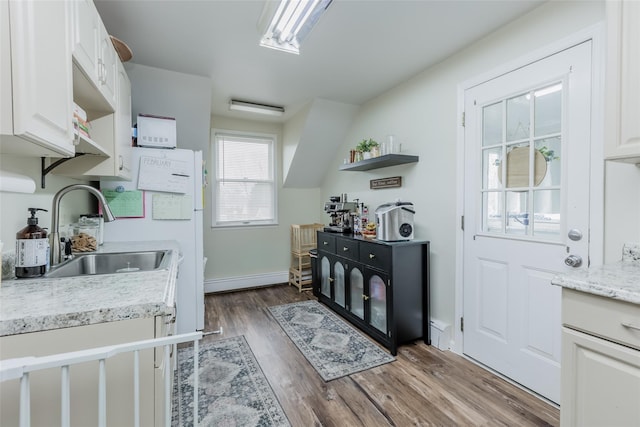 kitchen featuring a sink, open shelves, wood finished floors, and white cabinetry