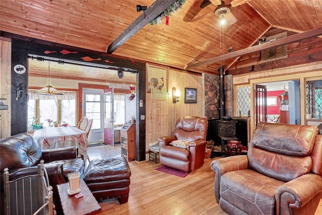 living room with a wood stove, wood finished floors, wood walls, wood ceiling, and vaulted ceiling with beams