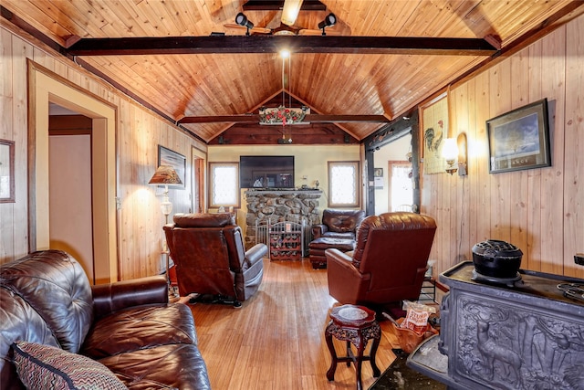 living room featuring wooden walls, vaulted ceiling with beams, a stone fireplace, wooden ceiling, and hardwood / wood-style flooring