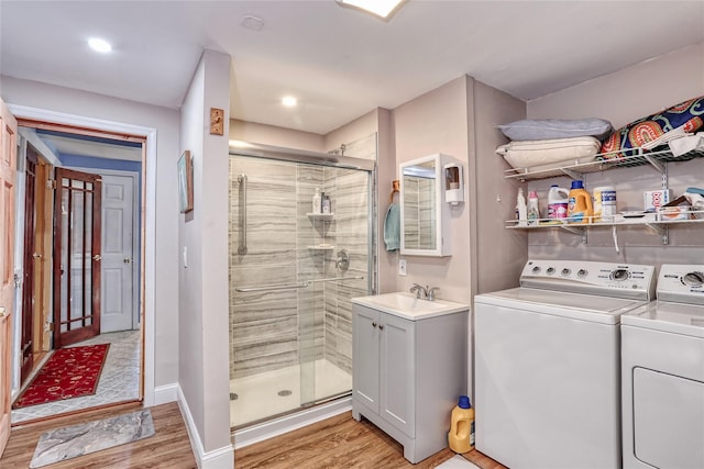 full bath with washer and clothes dryer, a shower stall, baseboards, and wood finished floors