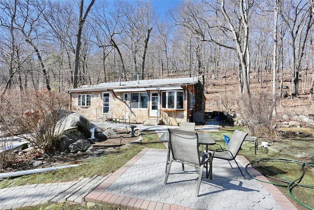 view of front facade with a patio area, stone siding, entry steps, and outdoor dining area