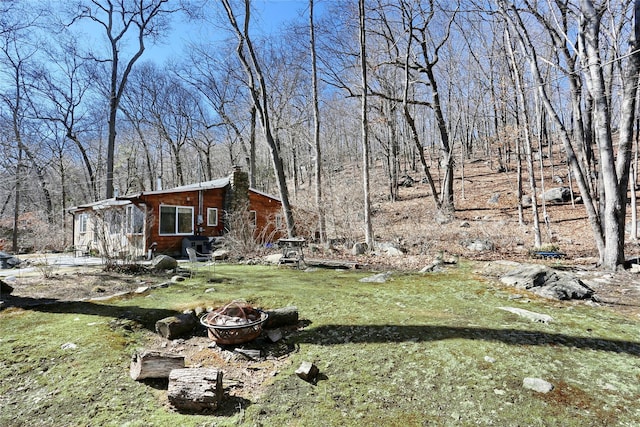 view of yard with a forest view and an outdoor fire pit