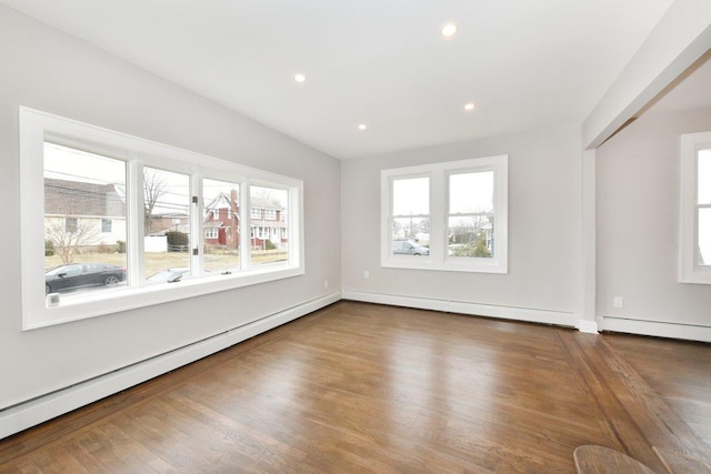 empty room with recessed lighting, a baseboard heating unit, and wood finished floors