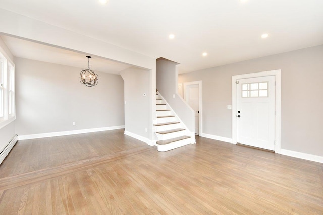 entryway featuring stairs, an inviting chandelier, light wood-style floors, and baseboards