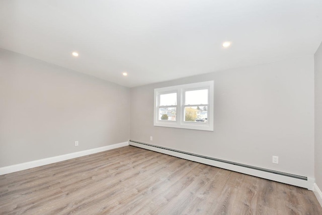 empty room featuring recessed lighting, a baseboard heating unit, baseboards, and wood finished floors