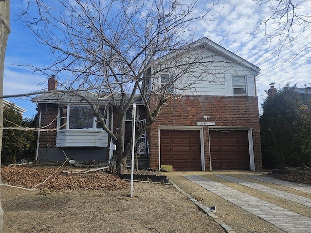 tri-level home featuring an attached garage, brick siding, driveway, and a chimney