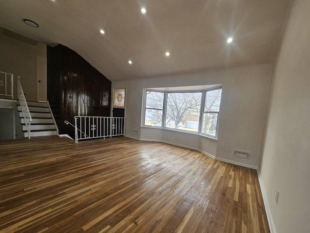 unfurnished living room with baseboards, wood finished floors, and vaulted ceiling