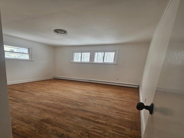 unfurnished room with a baseboard radiator, baseboards, and wood finished floors