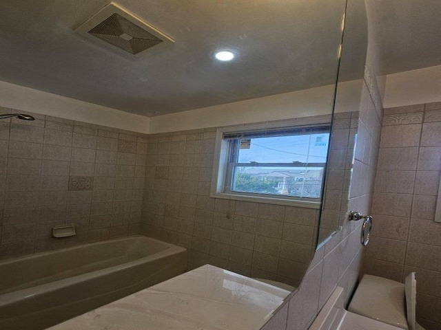 bathroom with visible vents and tile walls