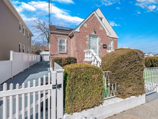 142-02 185th St, Springfield Gardens, NY 11413 - view of front of property with an outbuilding, a gate, a fenced front yard, roof mounted solar panels, and brick siding