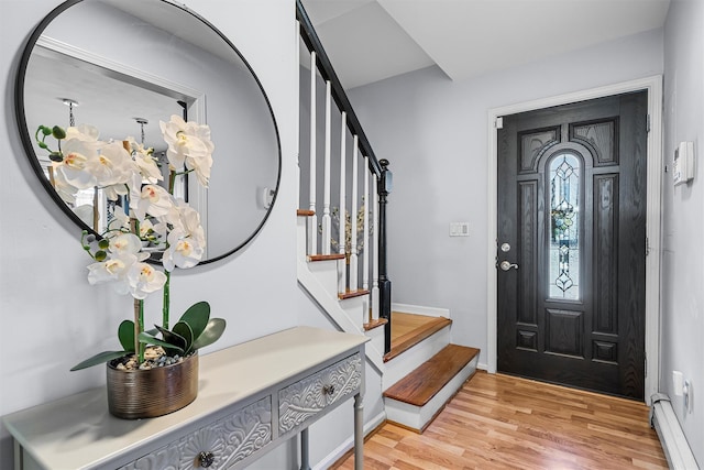 foyer with a baseboard radiator, light wood-style floors, and stairway