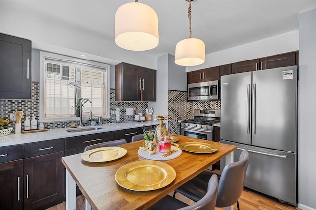 kitchen with a sink, stainless steel appliances, dark brown cabinetry, light countertops, and decorative backsplash