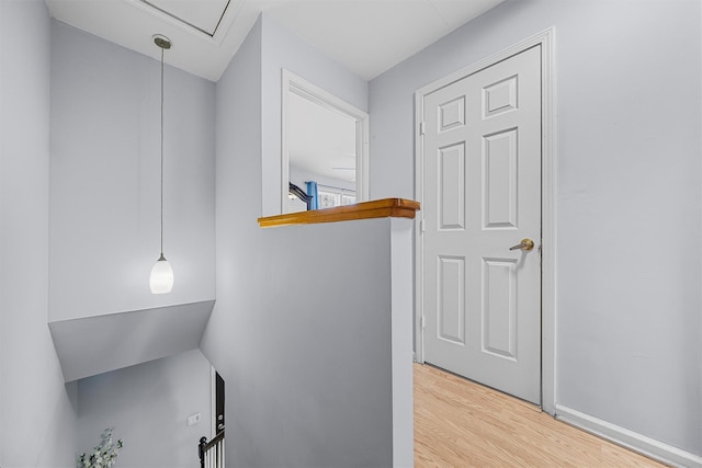 hall with attic access, baseboards, and wood finished floors