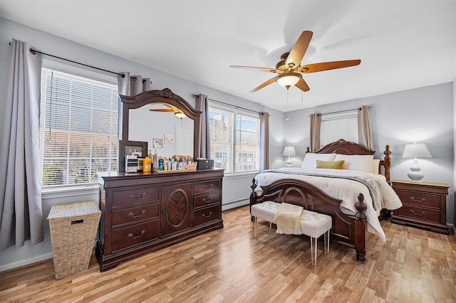 bedroom with a baseboard heating unit, a ceiling fan, light wood-type flooring, and baseboards