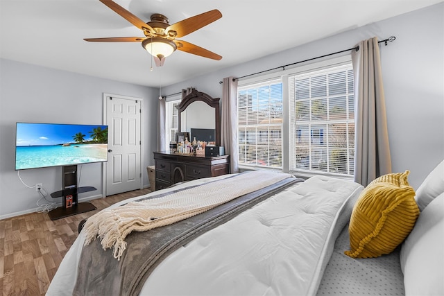 bedroom with baseboards, wood finished floors, and a ceiling fan