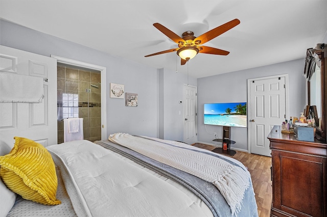 bedroom featuring connected bathroom, wood finished floors, baseboards, and ceiling fan