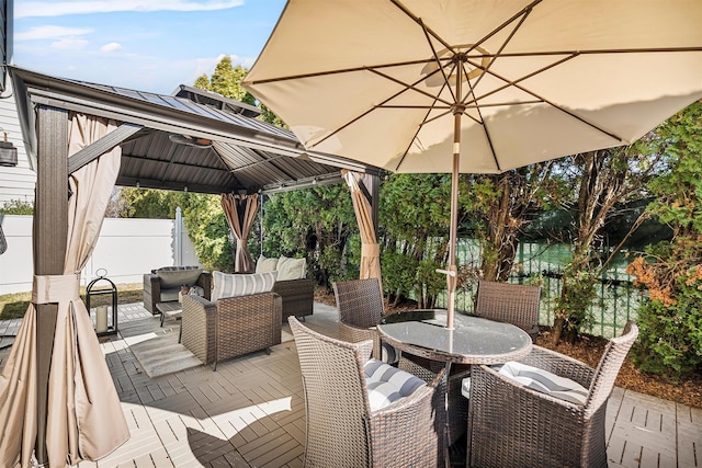 view of patio featuring a gazebo, an outdoor hangout area, outdoor dining space, and fence