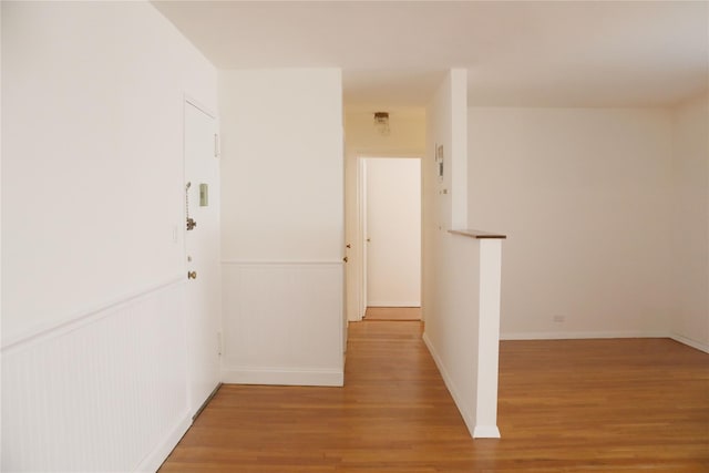 hall with light wood-type flooring and wainscoting