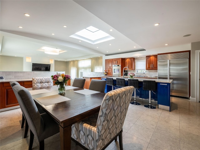 dining area with recessed lighting, a raised ceiling, light tile patterned flooring, and a skylight