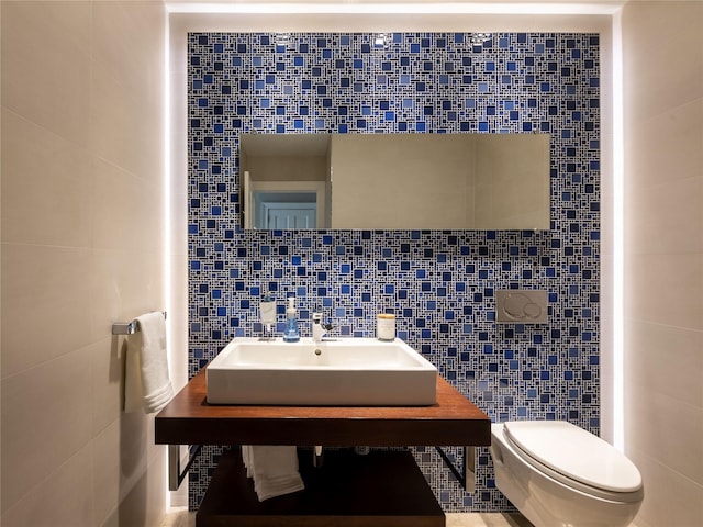 half bath featuring toilet, tile walls, and a sink