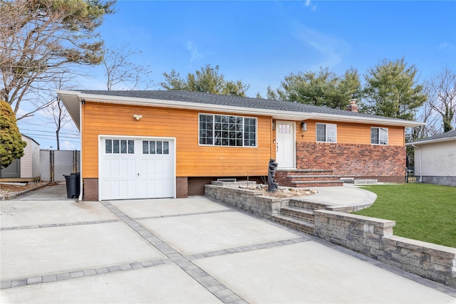 view of front of property with fence, an attached garage, concrete driveway, a front lawn, and brick siding