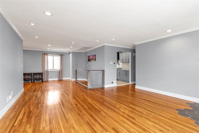 unfurnished living room with visible vents, baseboards, light wood-style flooring, recessed lighting, and ornamental molding