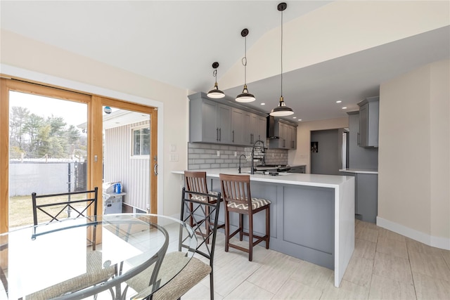 kitchen featuring a peninsula, gray cabinets, light countertops, vaulted ceiling, and tasteful backsplash