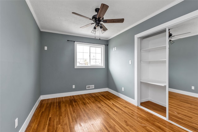 unfurnished bedroom featuring a textured ceiling, crown molding, baseboards, and hardwood / wood-style floors