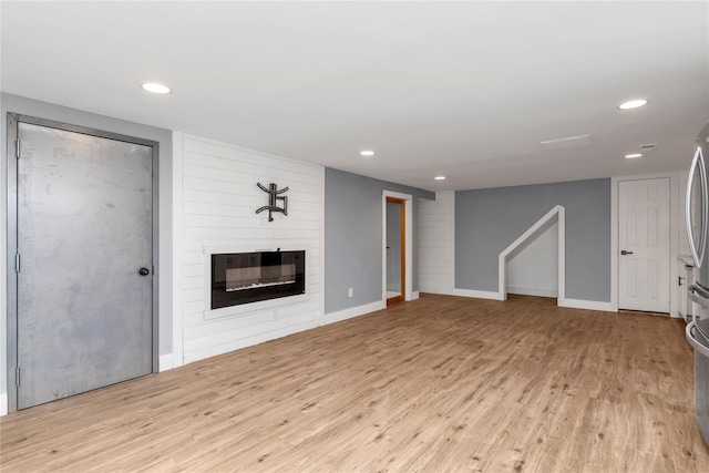 unfurnished living room with recessed lighting, a large fireplace, baseboards, and wood finished floors