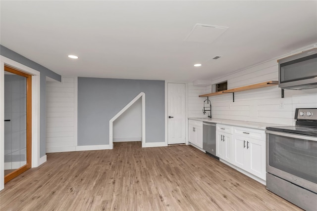 kitchen featuring light countertops, light wood-style flooring, appliances with stainless steel finishes, white cabinets, and open shelves