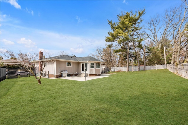 rear view of property featuring a yard, a patio, and a fenced backyard