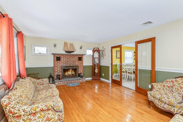 living room with hardwood / wood-style flooring, a fireplace, visible vents, and baseboards