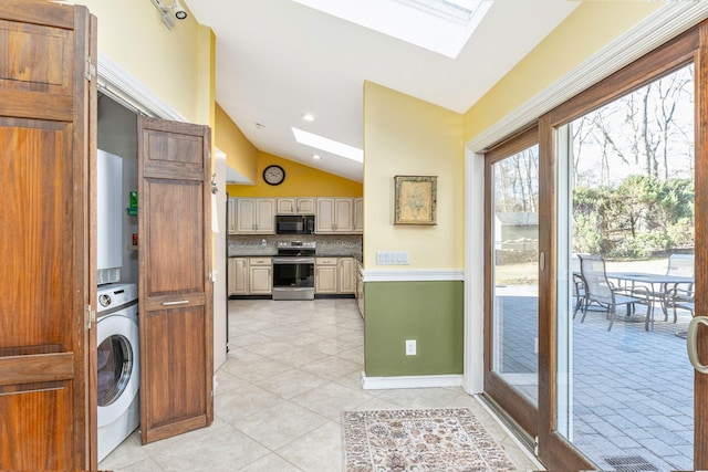 kitchen featuring black microwave, decorative backsplash, vaulted ceiling with skylight, washer / dryer, and electric stove