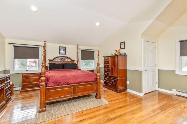 bedroom featuring a baseboard heating unit, lofted ceiling, multiple windows, and light wood finished floors