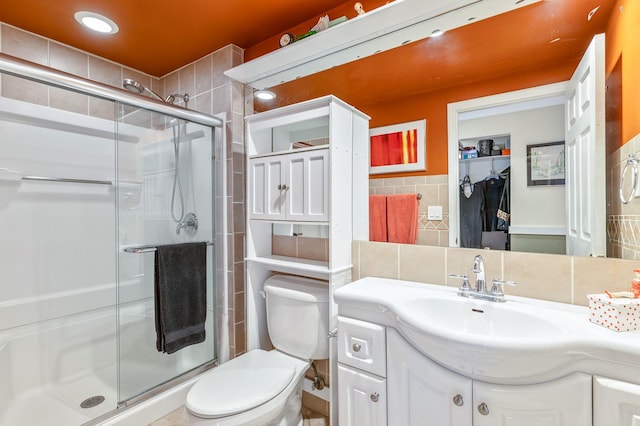 full bathroom with toilet, tile walls, a stall shower, and vanity