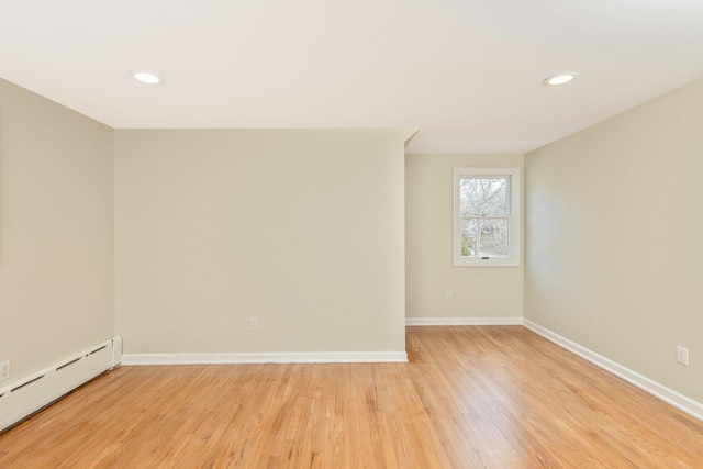 spare room featuring light wood-type flooring, a baseboard heating unit, baseboards, and recessed lighting