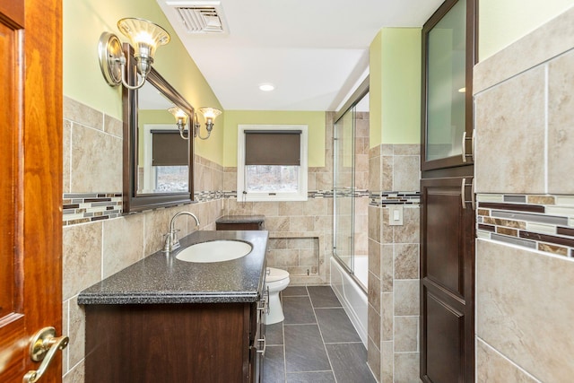 bathroom with visible vents, enclosed tub / shower combo, tile patterned flooring, tile walls, and toilet