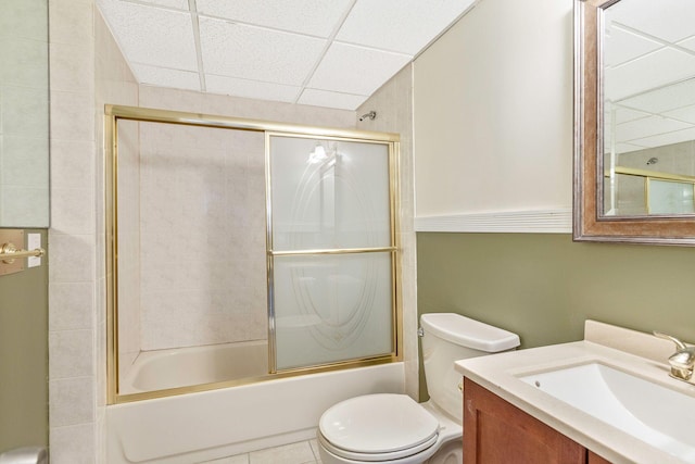 full bath with vanity, shower / bath combination with glass door, tile patterned flooring, a paneled ceiling, and toilet